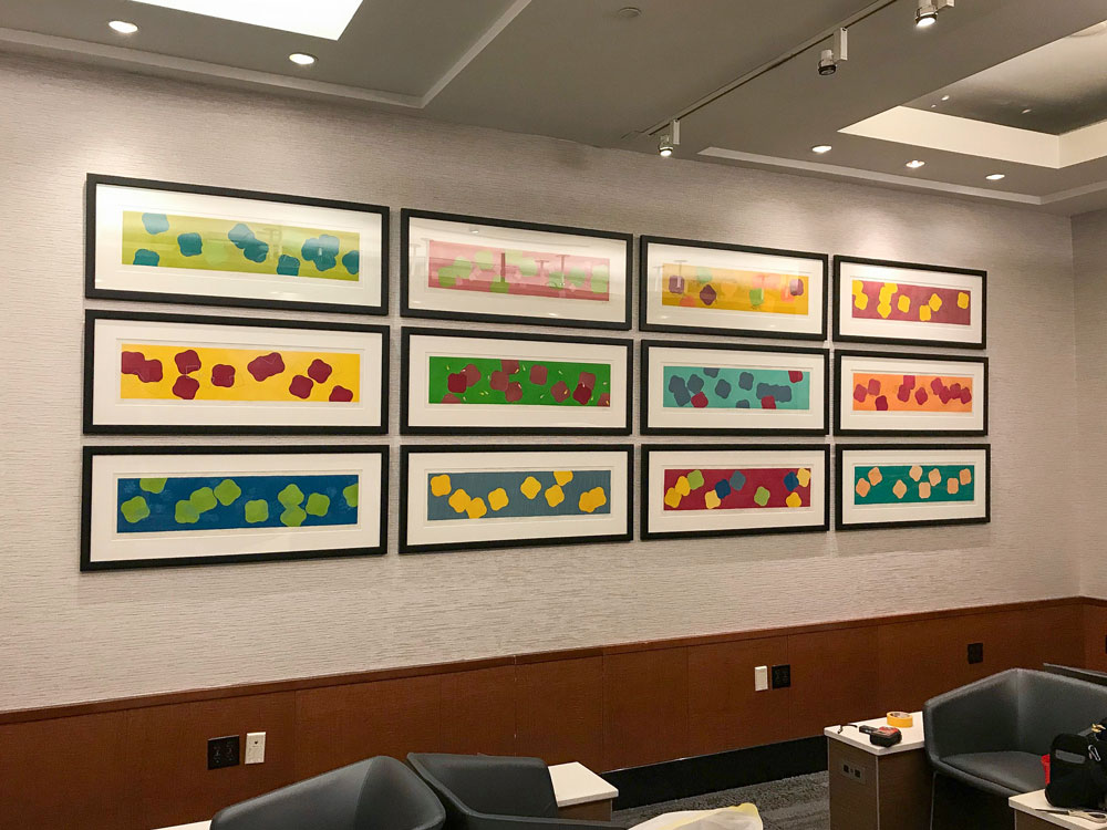 Mark of Oakland Art Installers hanging a 12 piece art collage